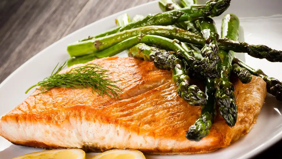 Grilled salmon and asparagus on wooden table