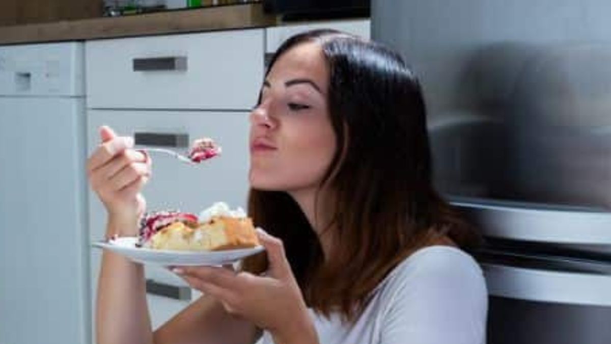 woman eating a cake at night